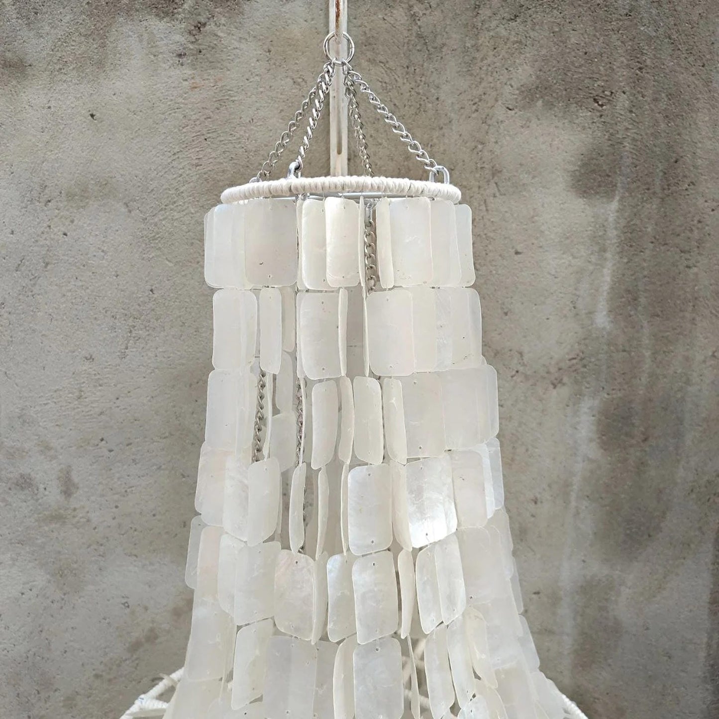 White seashell chandelier against a textured gray wall