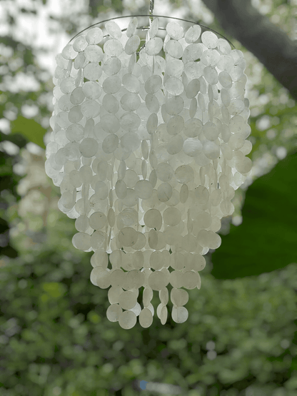 White capiz shell chandelier against a blurred green background