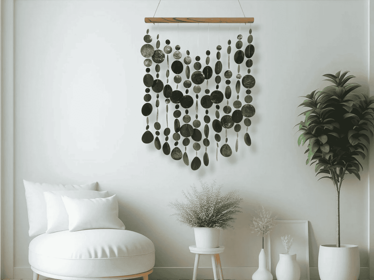 Black capiz shell wall hanging in a room with a white wall, plant, and chair.