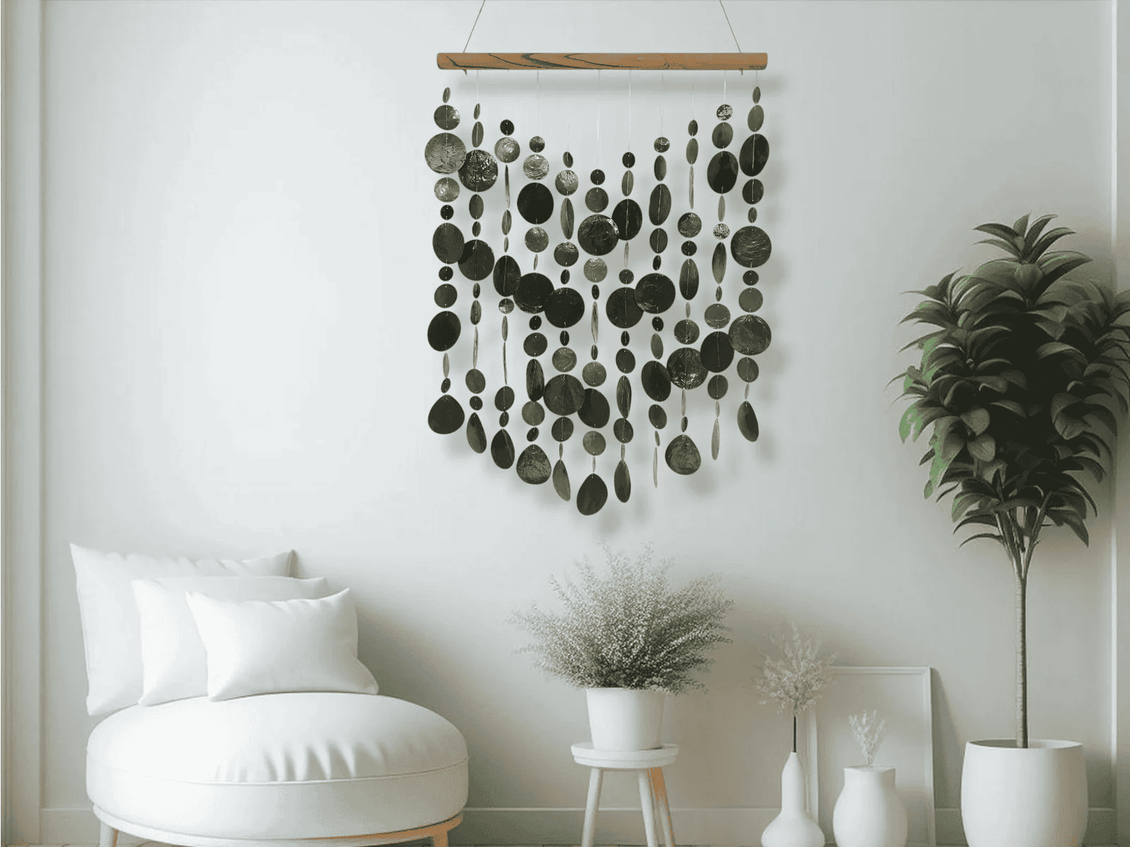 Black capiz shell wall hanging in a room with a white wall, plant, and chair.