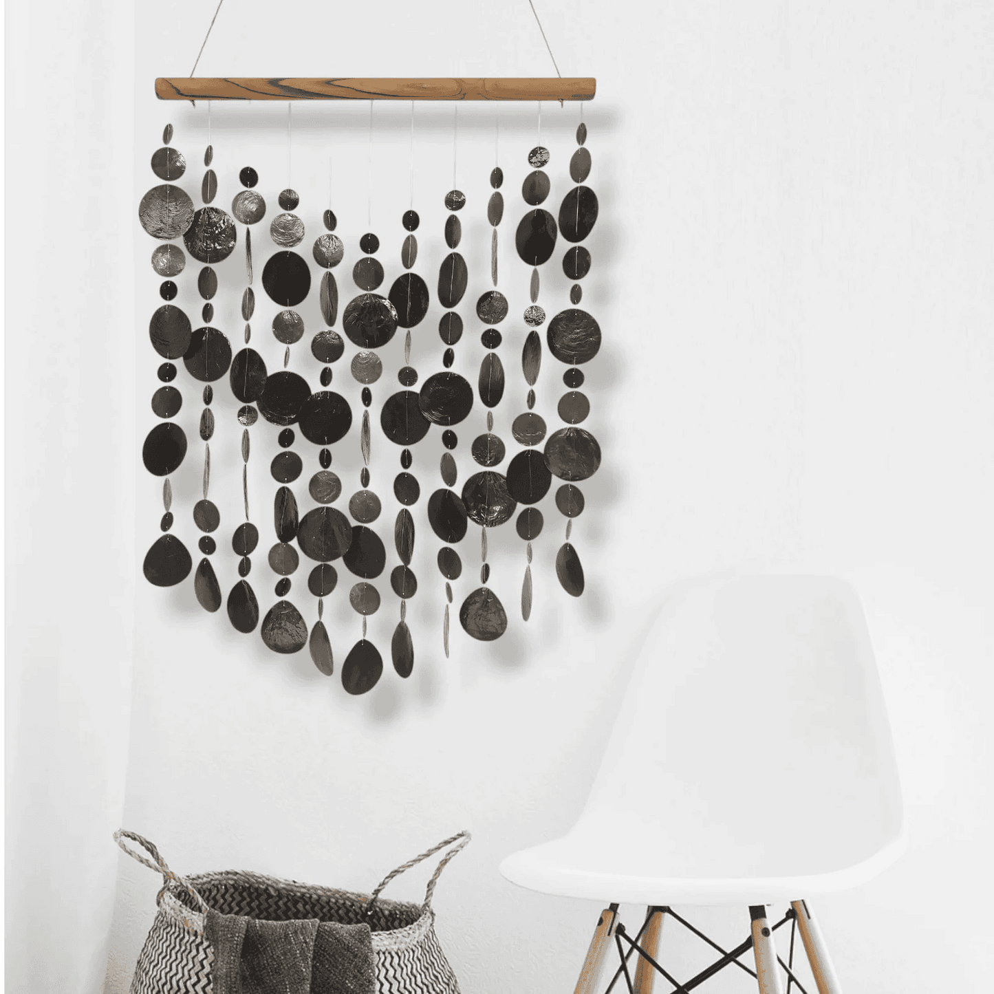 Capiz shell wall hanging with black circular patterns on a white background