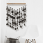 Capiz shell wall hanging with black circular patterns on a white background