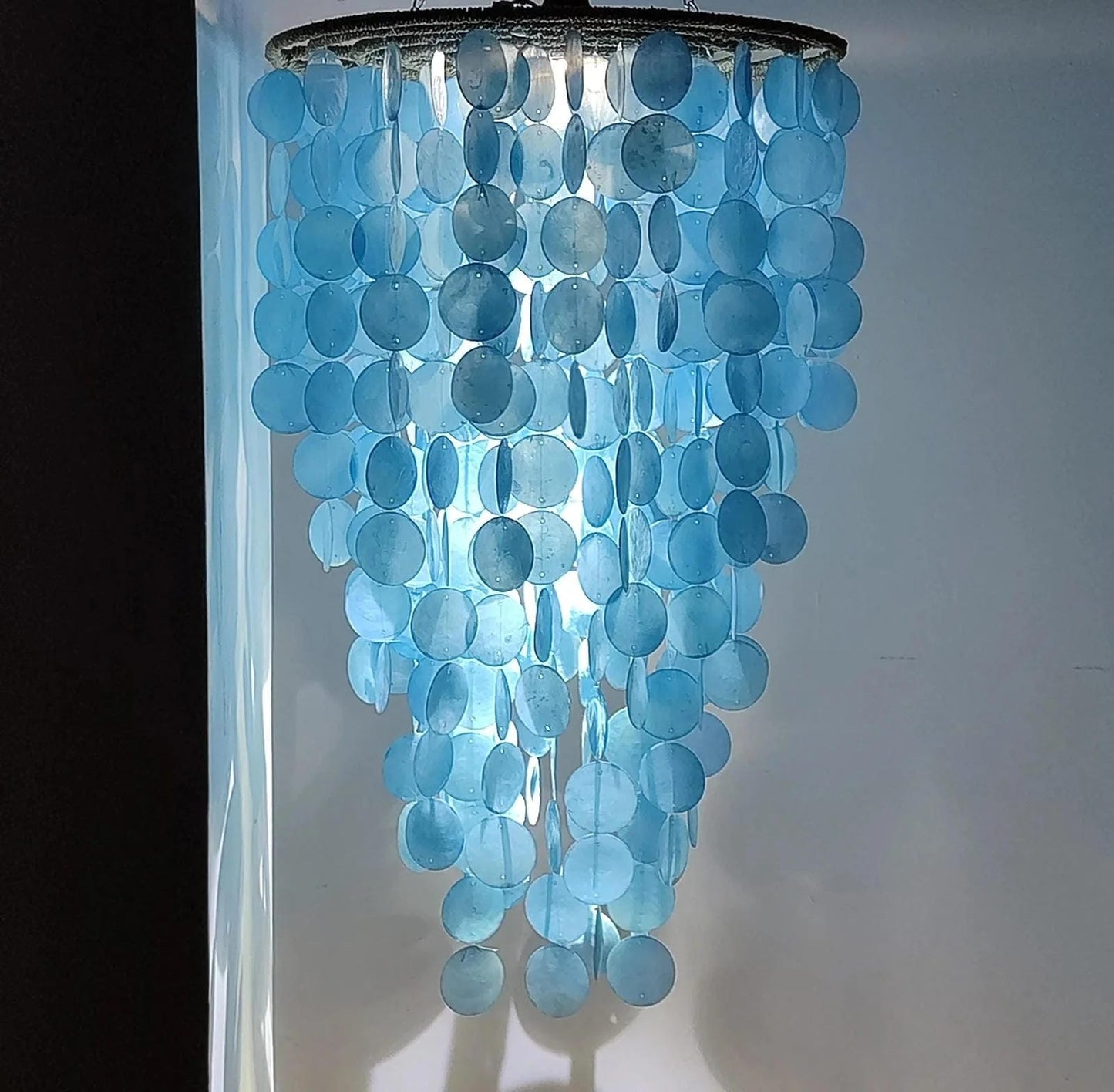 Blue capiz chandelier against a white wall