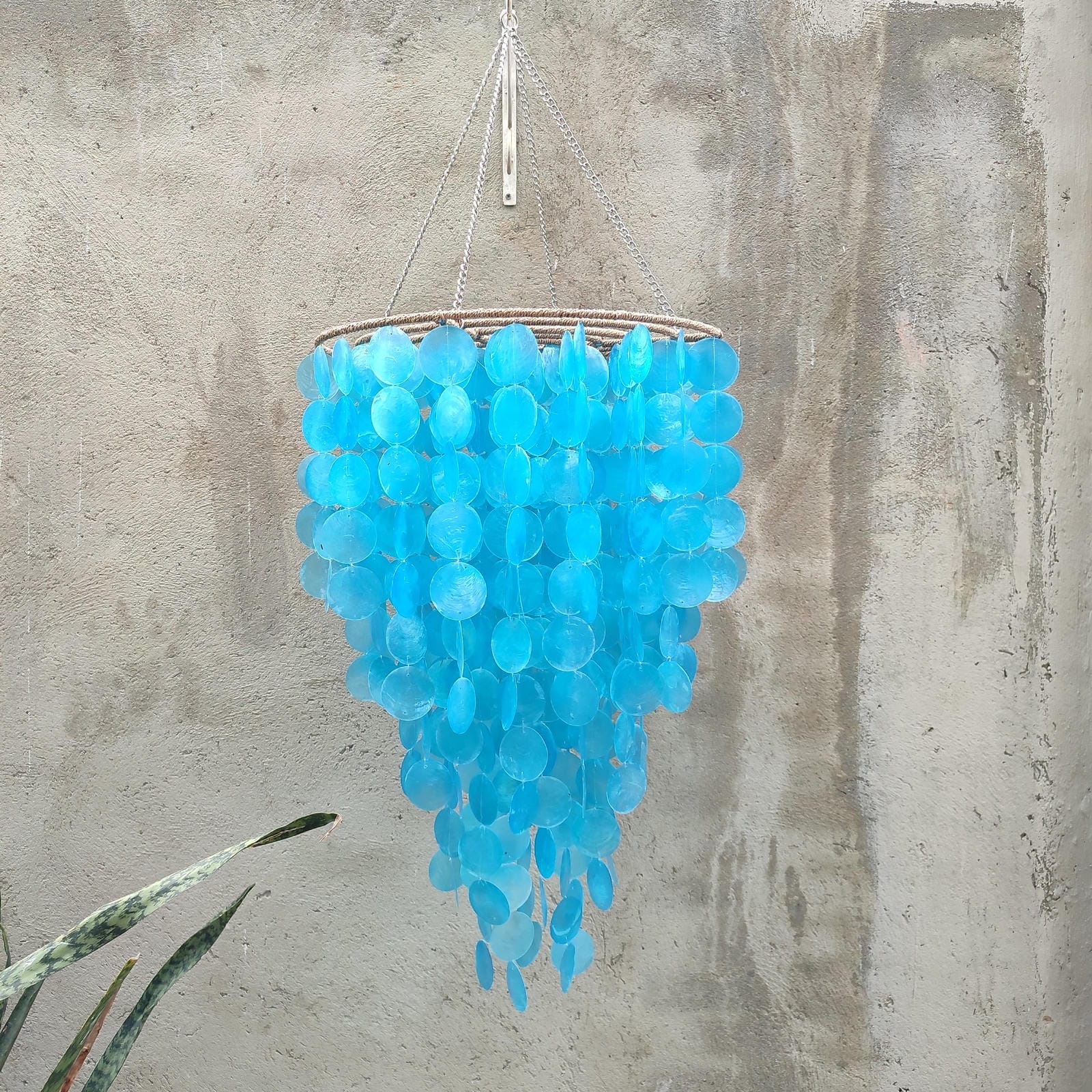 Blue capoz chandelier hanging against a concrete wall