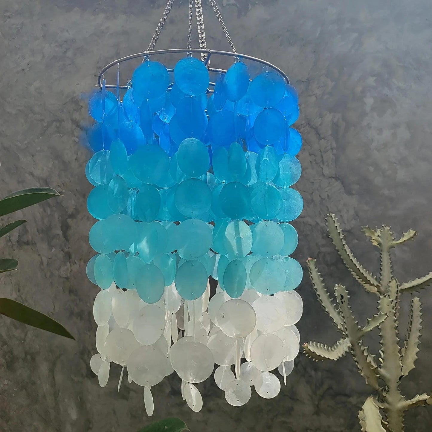 Decorative chandelier with blue and white capiz shell against a natural background