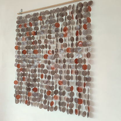 Textile wall art with circular patterns in shades of brown and gray on a white background