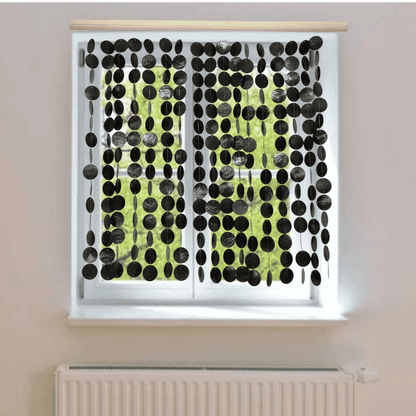 Window with black capiz shell curtain on a light-colored wall