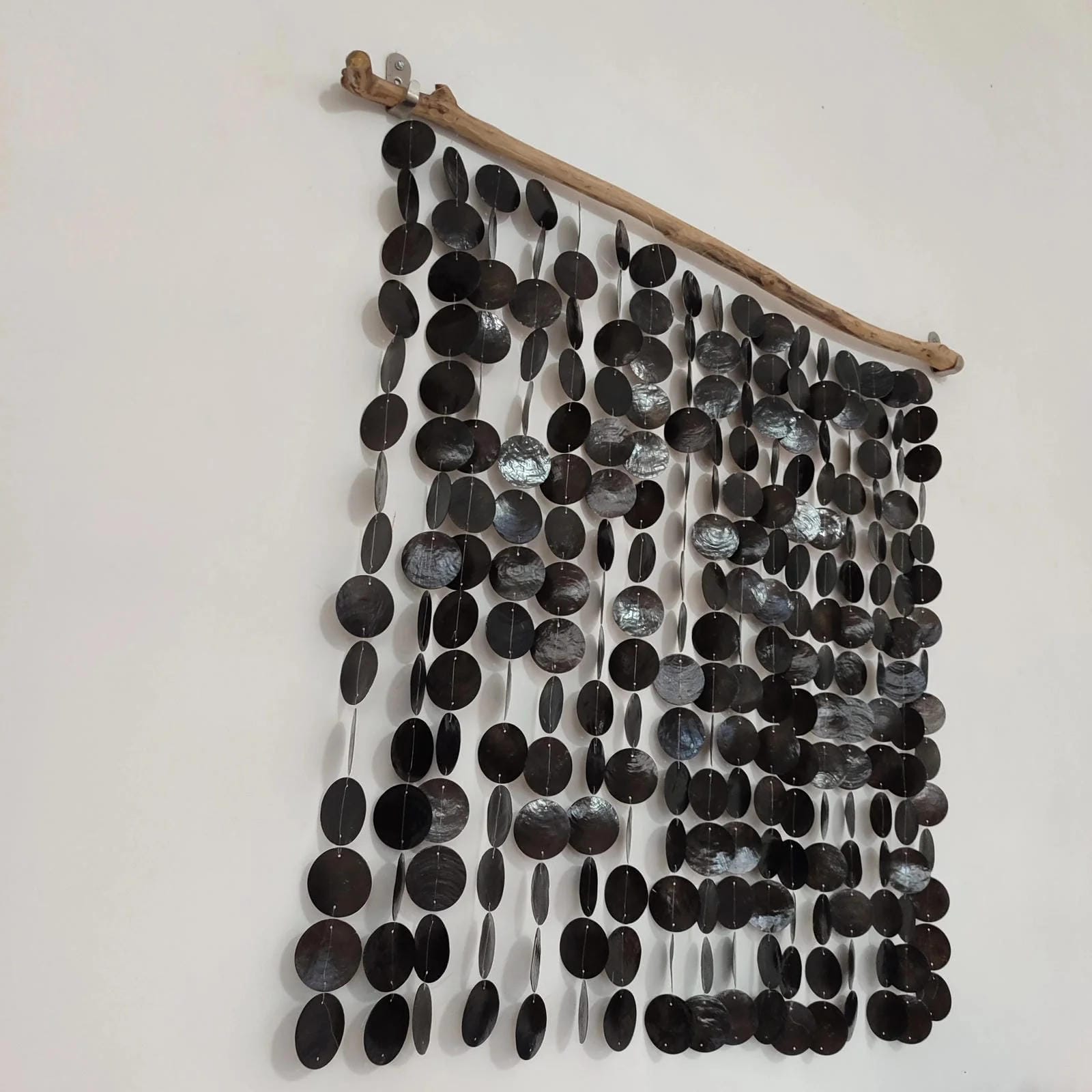 Wall art made of black capiz shell and a branch on a white background
