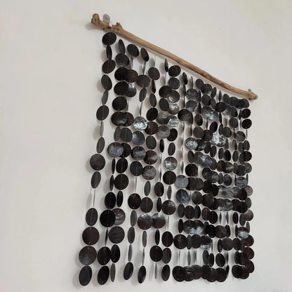 Wall art made of black capiz shell and a branch on a white background