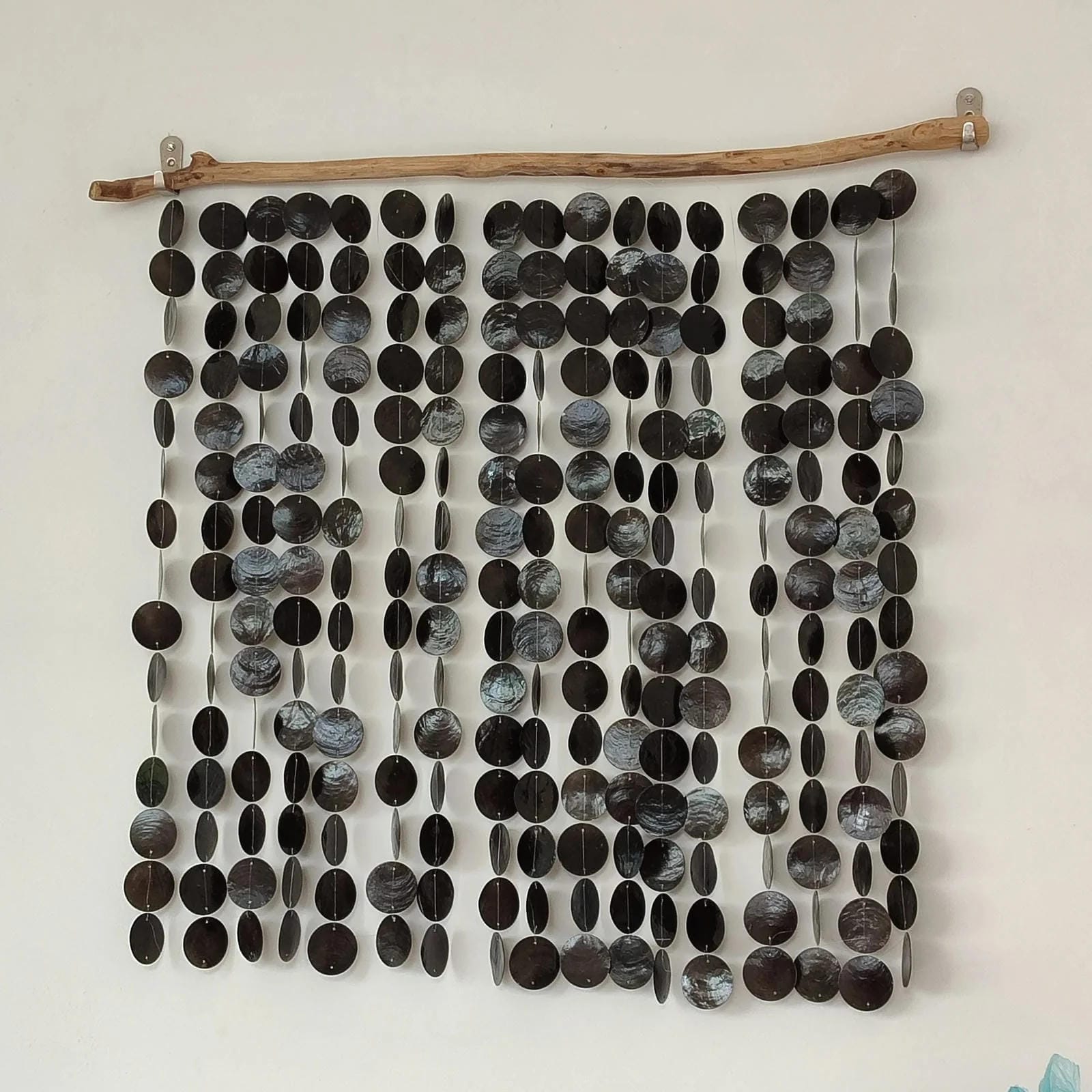 Wall art made of black circular capiz shell on a white wall