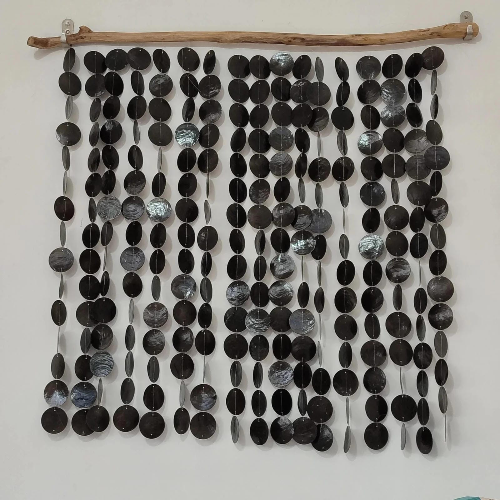 Wall art made of black and gray capiz shell on a white background