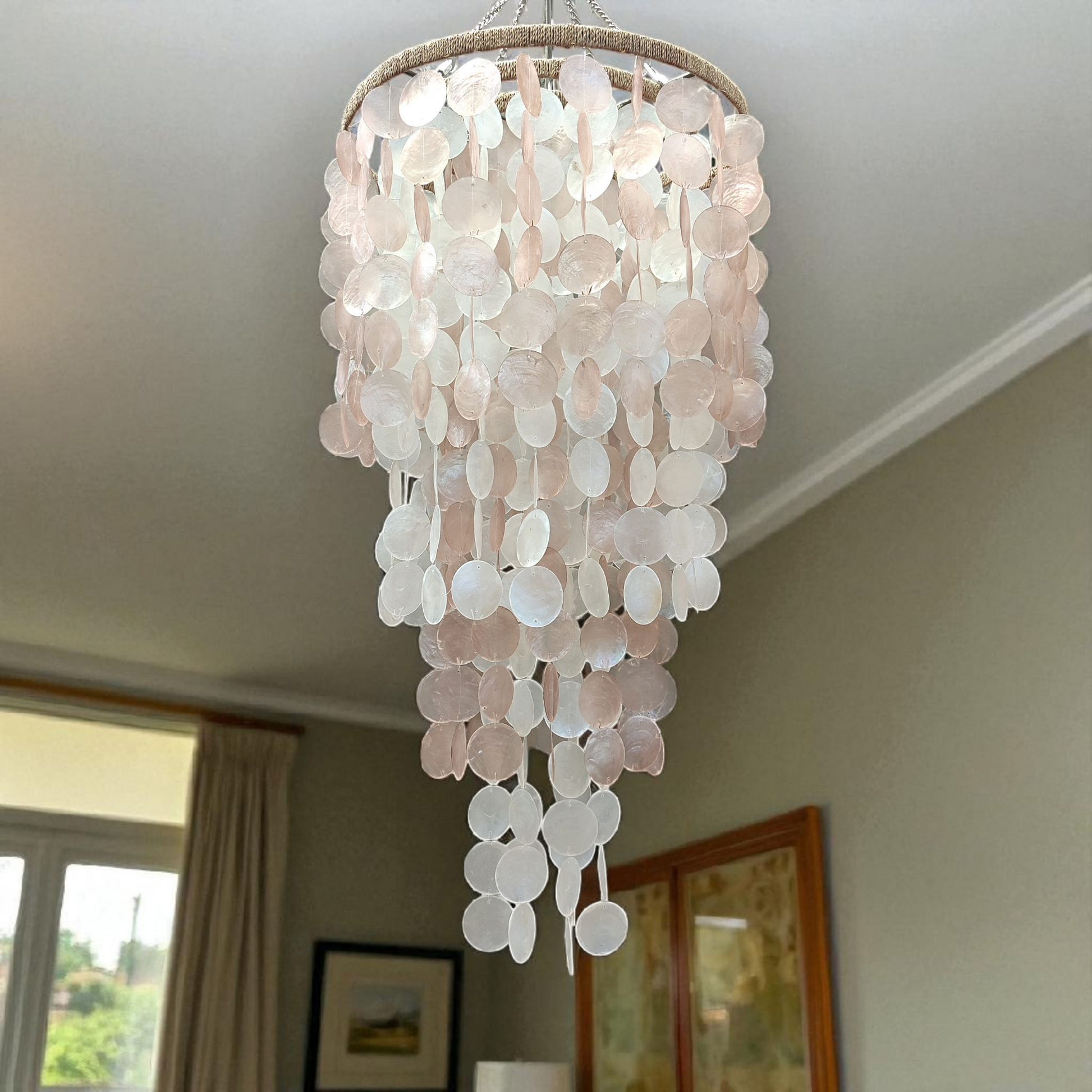 Chandelier made of circular light pink stones hanging from a ceiling.