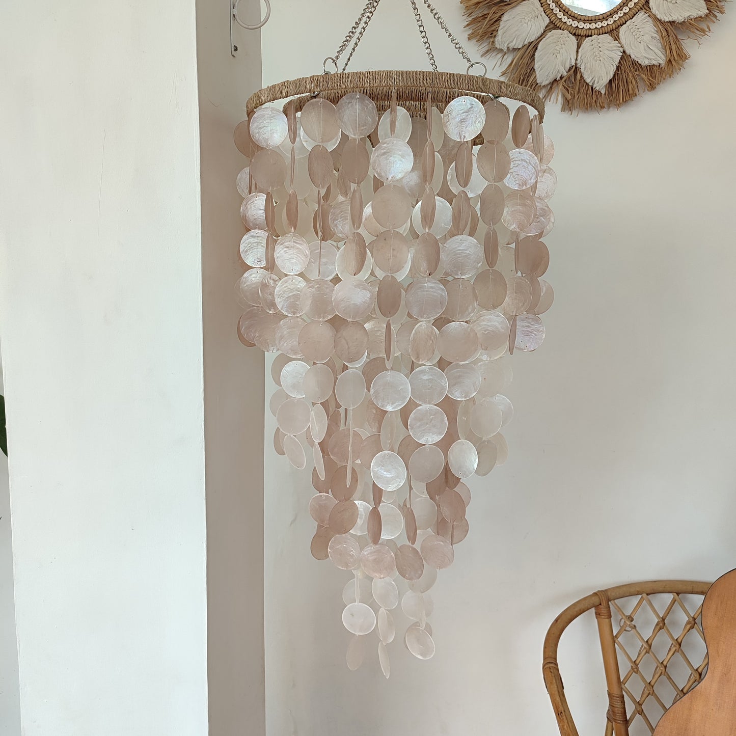 Decorative chandelier with circular elements hanging against a neutral wall.