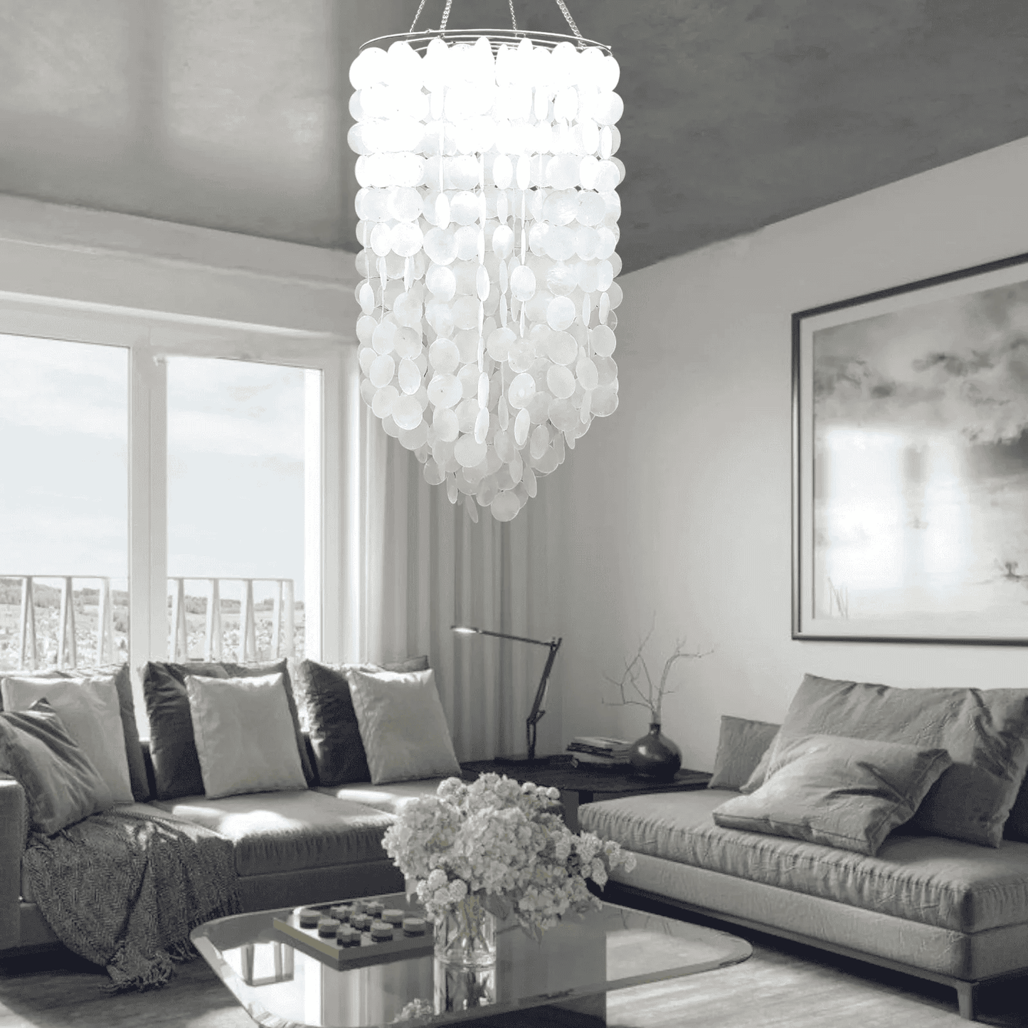 Modern living room with a capiz shell  chandelier, gray sofa, and large windows.