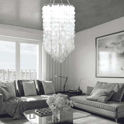 Modern living room with a capiz shell  chandelier, gray sofa, and large windows.