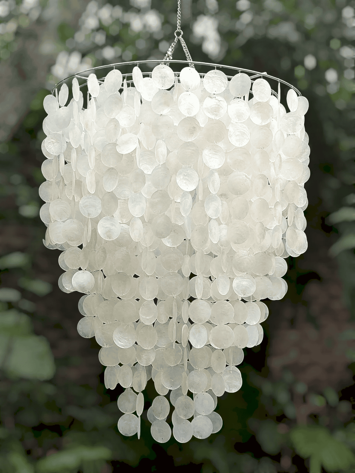 White capiz shell chandelier hanging against a blurred natural background