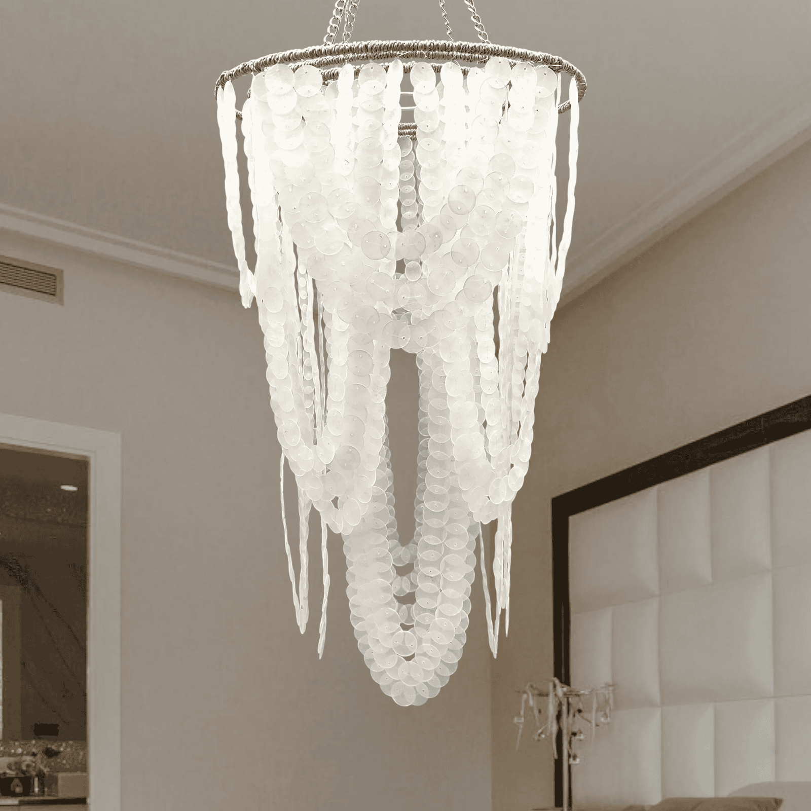 Small capiz shell chandelier hanging in a room with neutral walls and a mirror.