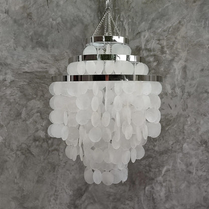 Chandelier with white capiz shell against a gray textured wall