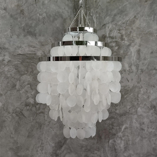 Chandelier with white capiz shell against a gray textured wall