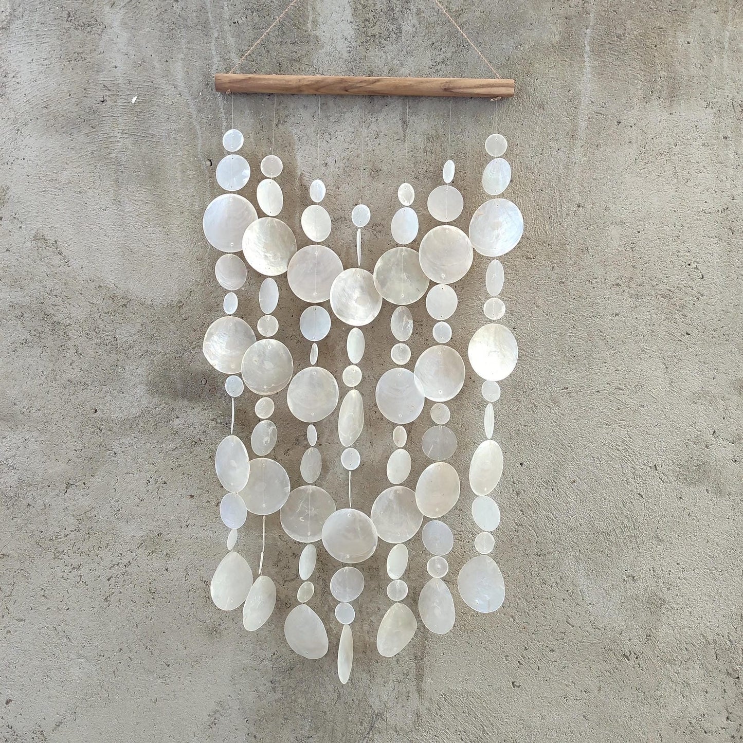 Decorative capiz shellwall hanging with white circular shell on a concrete wall