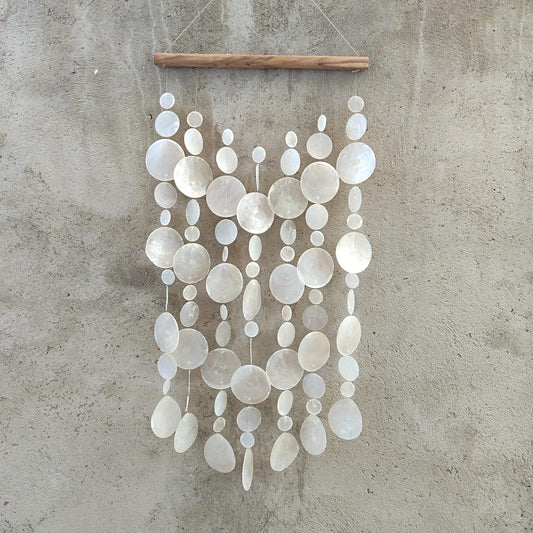 Decorative capiz shellwall hanging with white circular shell on a concrete wall
