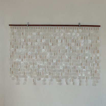 White capiz shell wall decor hanging in the white wall with brown wood rod 