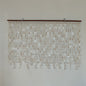 White capiz shell wall decor hanging in the white wall with brown wood rod 