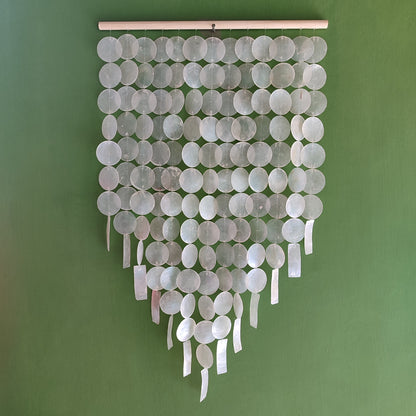 Decorative wall hanging with round capiz shell on a green background