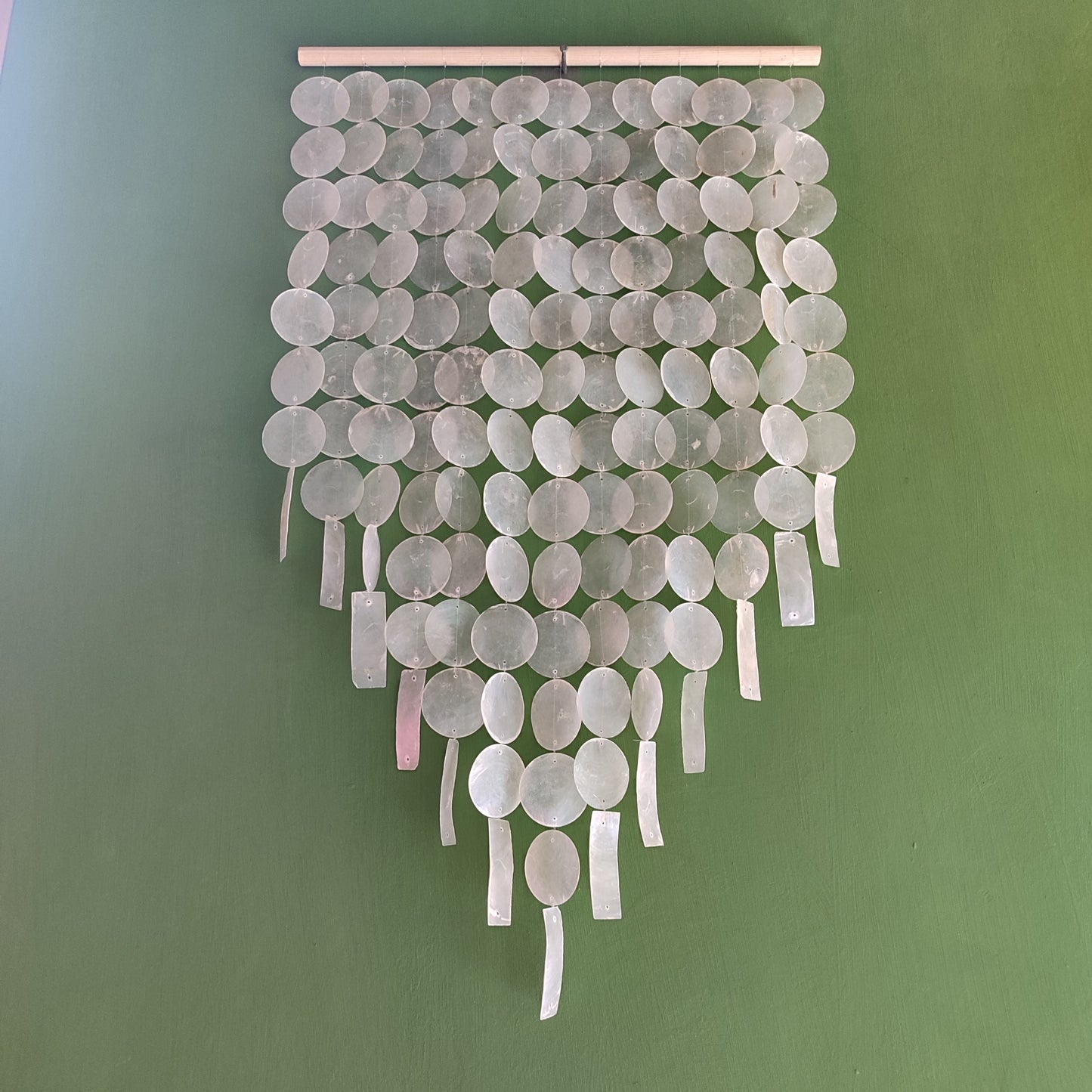 Decorative wall hanging with round capiz shell on a green background