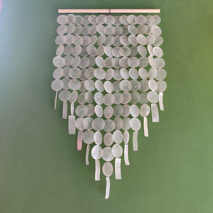 Decorative wall hanging with round capiz shell on a green background