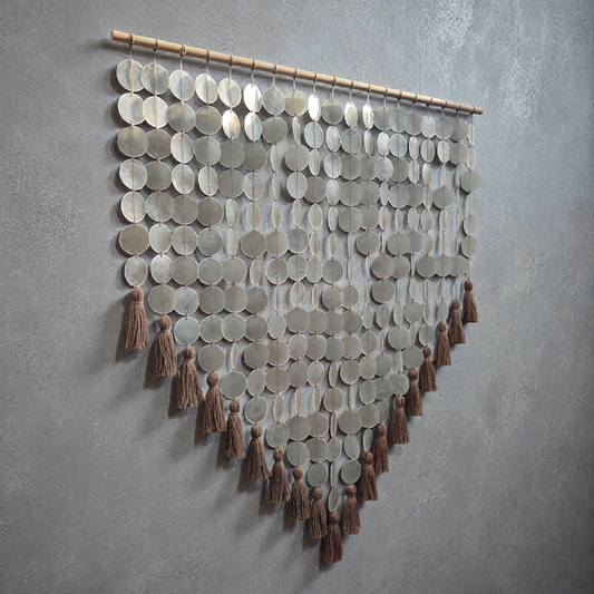 Decorative wall hanging made from capiz shell and tassels on a gray wall