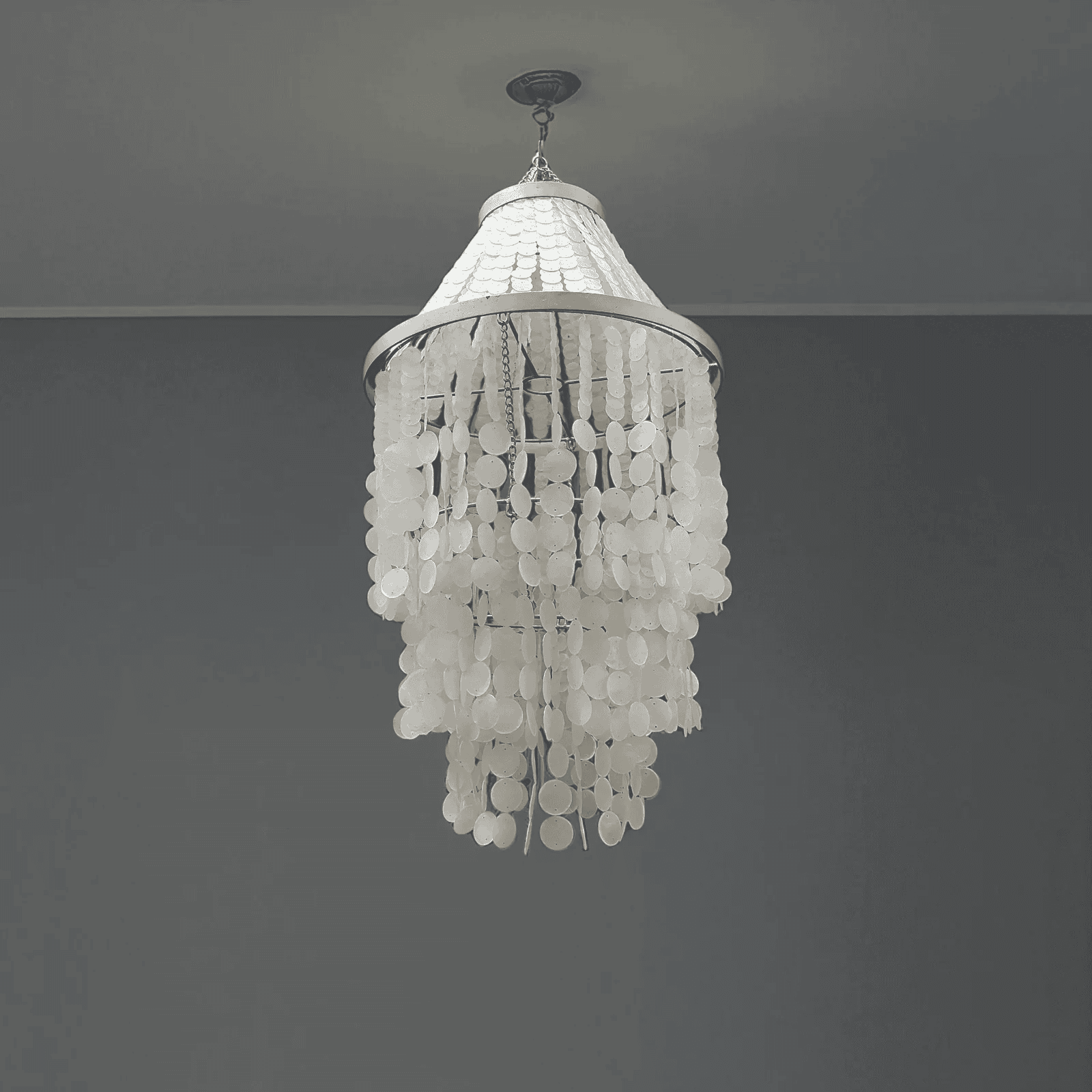 White chandelier hanging against a gray wall