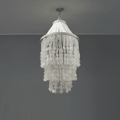 White chandelier hanging against a gray wall