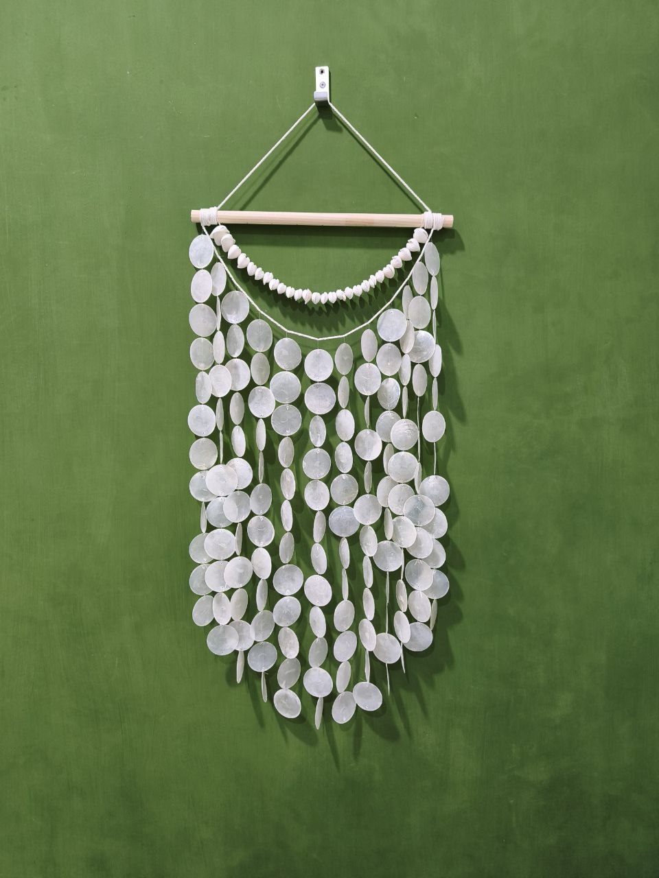 White circular wall hanging on a green background