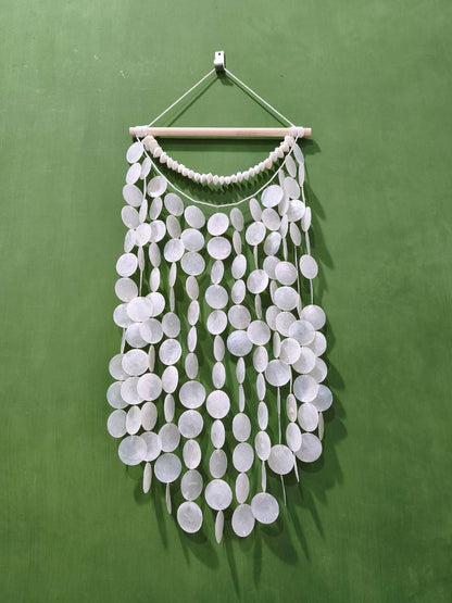 White decorative wall hanging with circular elements on a green background