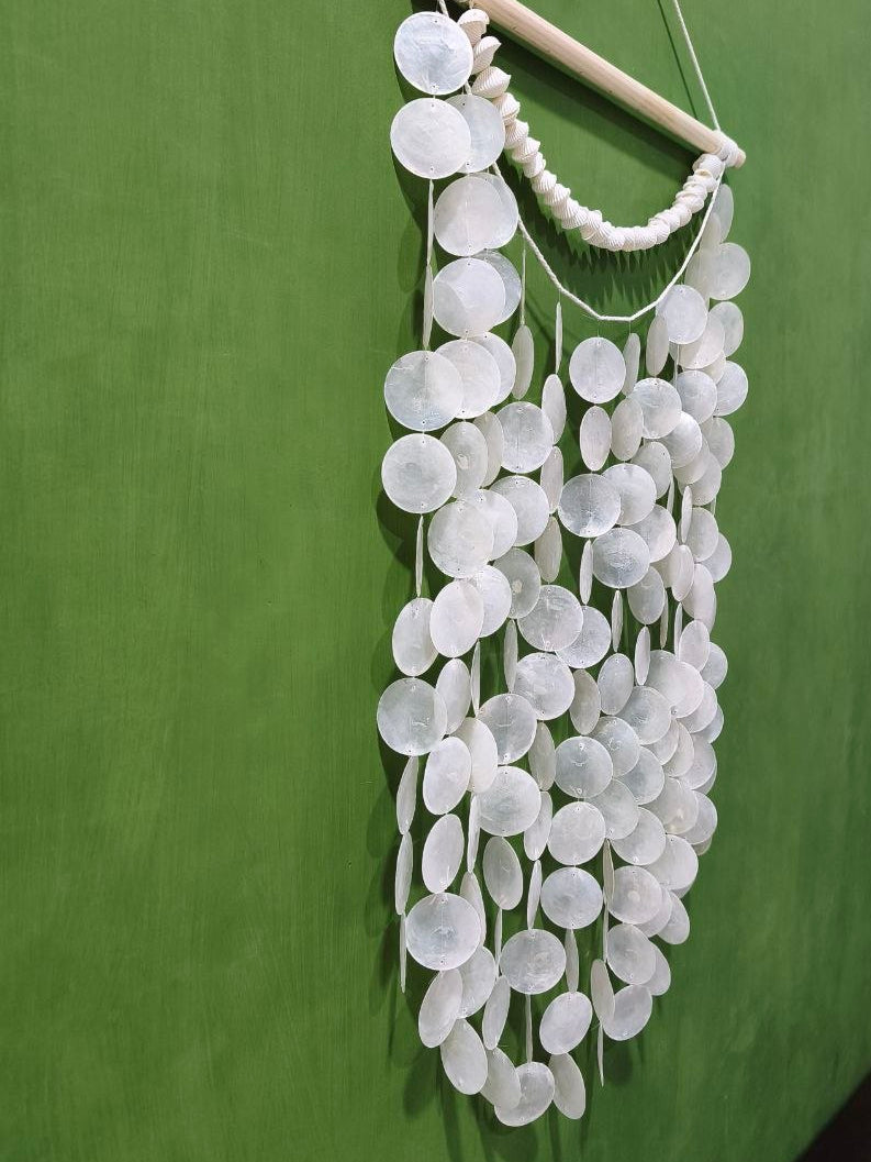 Decorative wall hanging with white circular discs on a green wall.