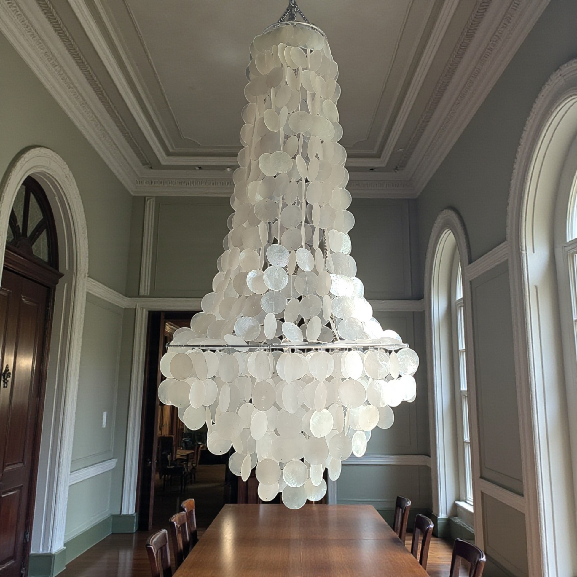 Large chandelier hanging in a room with a wooden table and chairs.