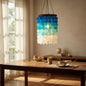Colorful pendant light hanging above a wooden dining table with a bowl of fruit and a plant.