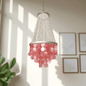 Chandelier with pink capiz shell in a room with framed pictures on the wall.