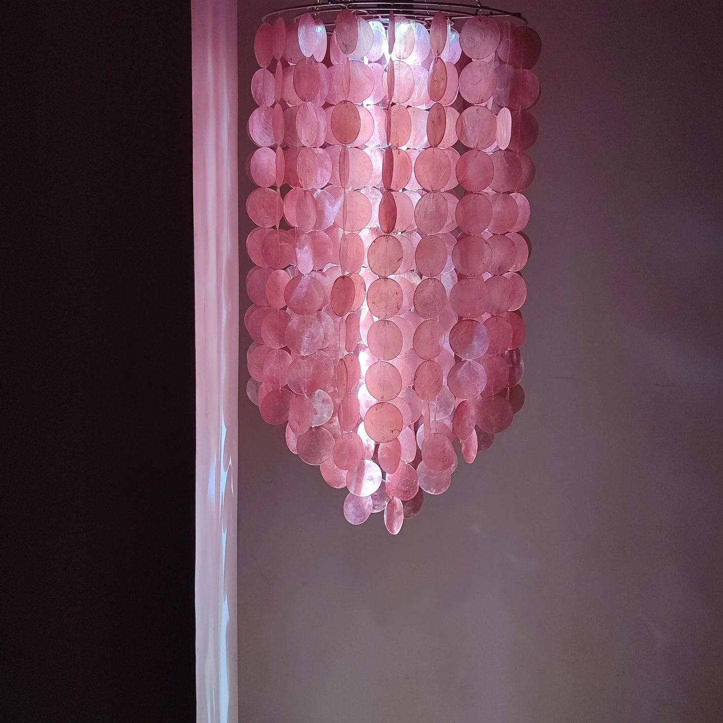 Pink capoz shell chandelier against a neutral wall