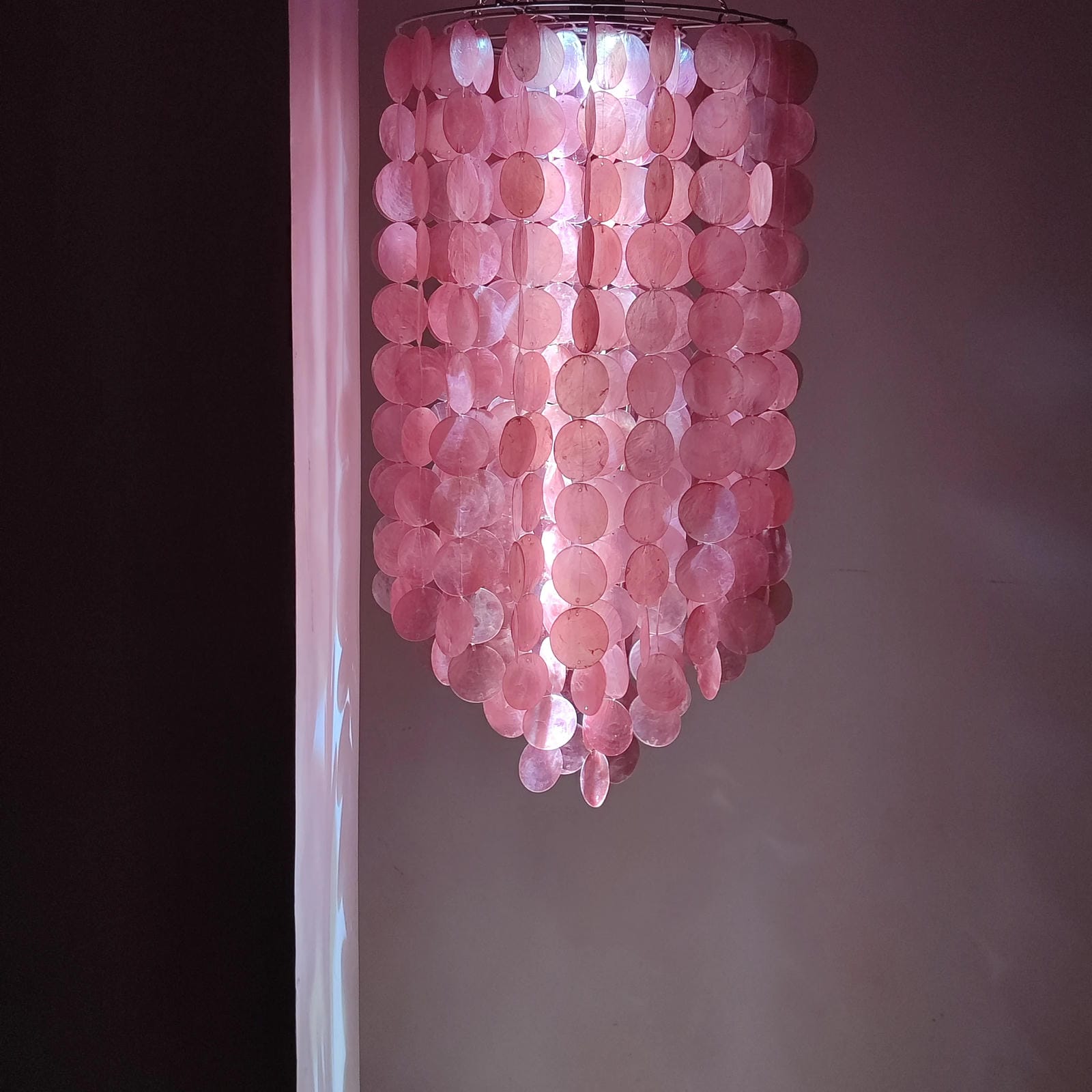 Pink capoz shell chandelier against a neutral wall