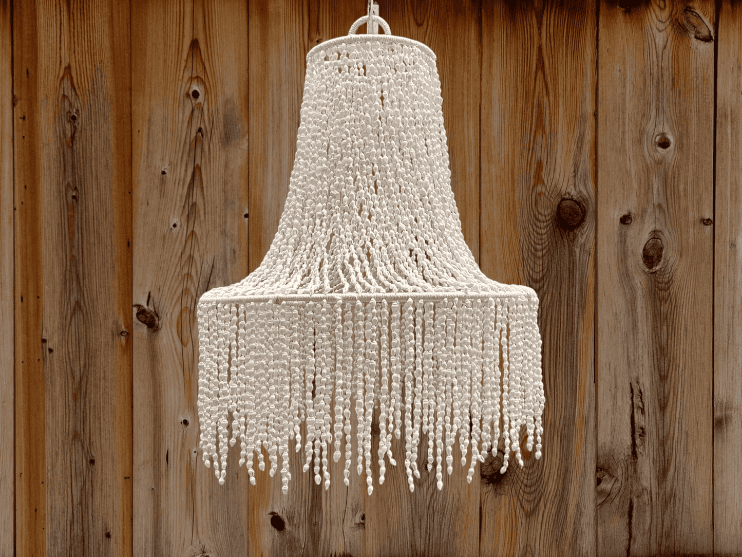 Seashell chandelier hanging against a wooden background