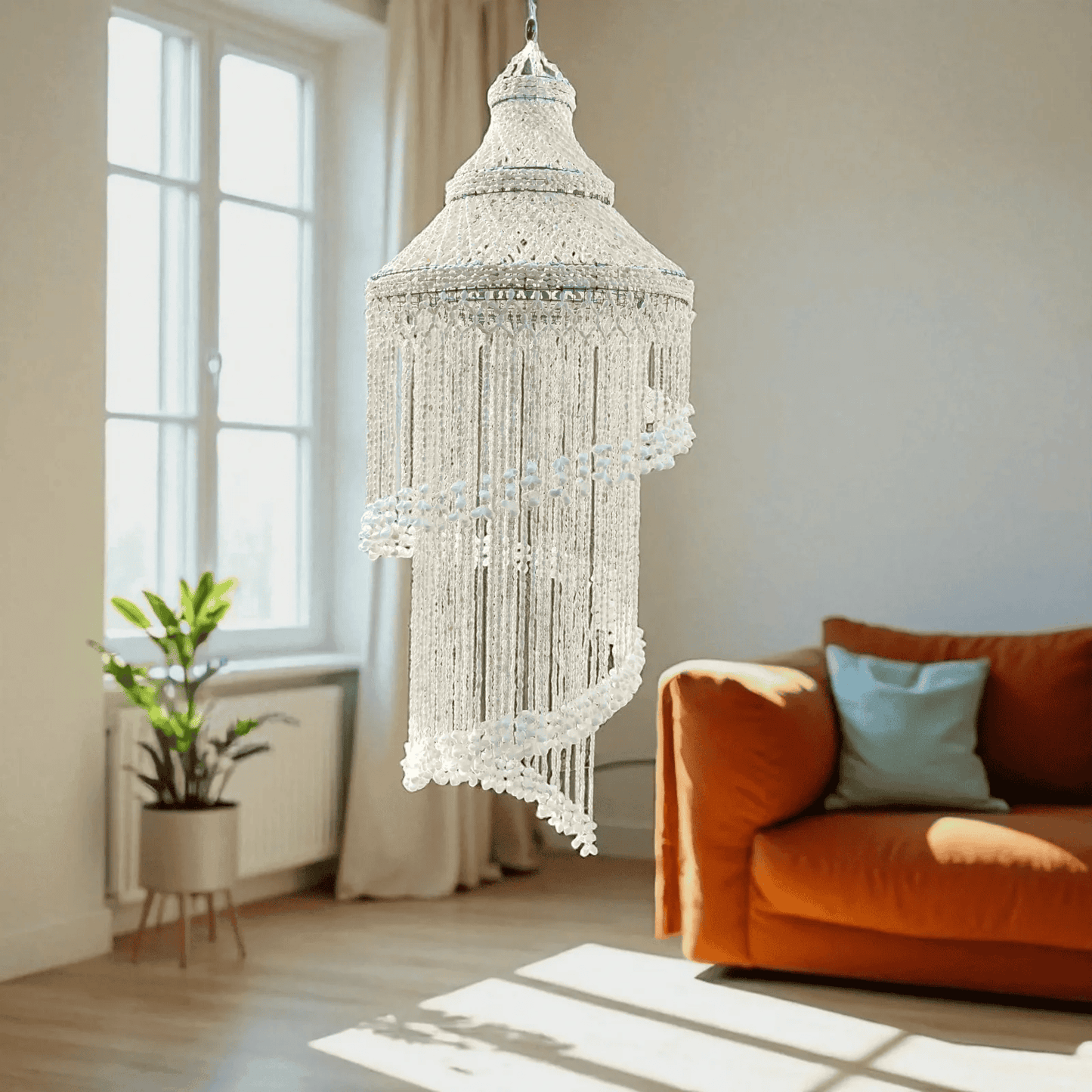 Seashell chandelier hanging in a living room with an orange sofa and plant.