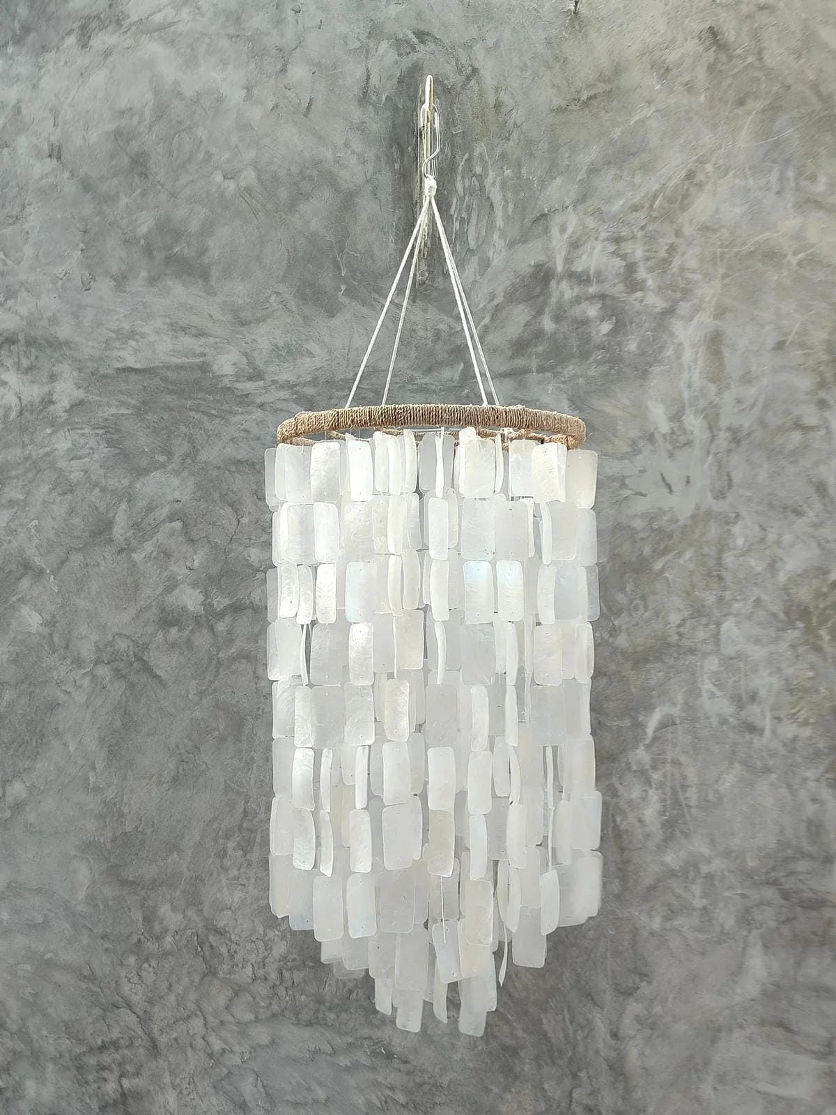 Chandelier made of white shell pieces on a gray background
