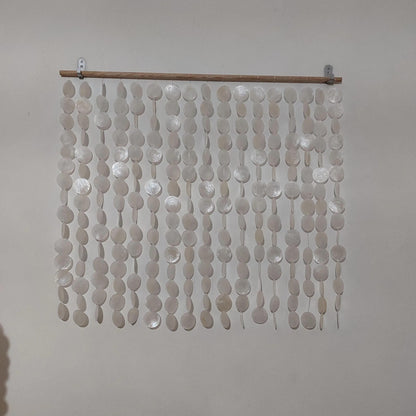Decorative capiz shell wall hanging on a plain background